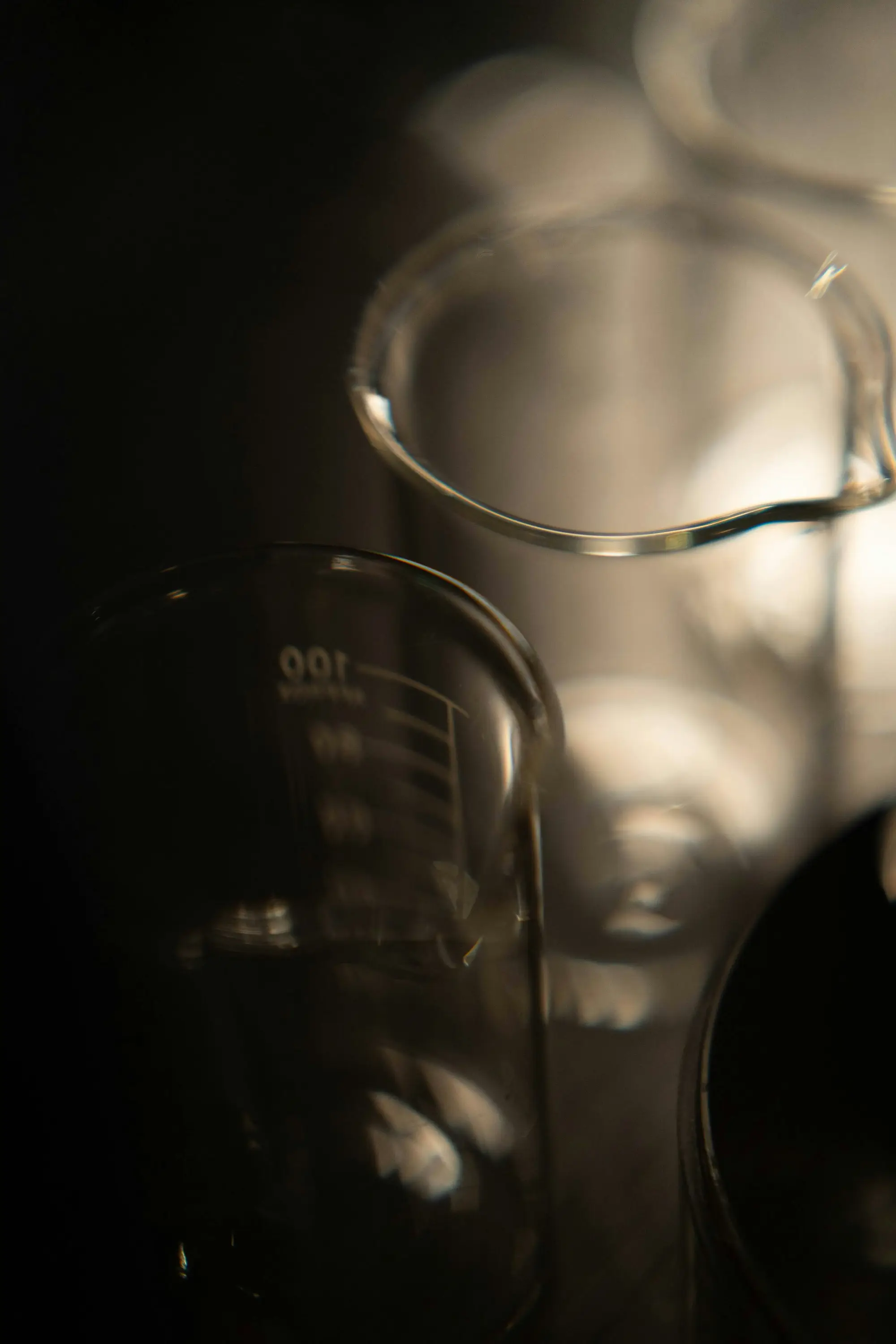 Glass beakers and laboratory glassware on a dark background, clinical study imagery.